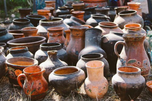 Clay vessels in a variety of shapes, colors, and sizes arranged outdoors