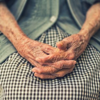 Hands of an elder resting in her apron.