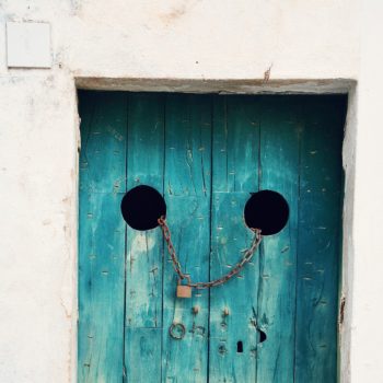 Old blue door with a chain and padlock hung between two round holes