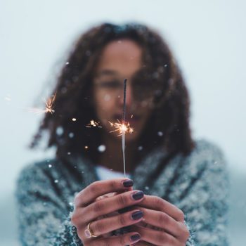 Woman extends her hand with a sparkler.