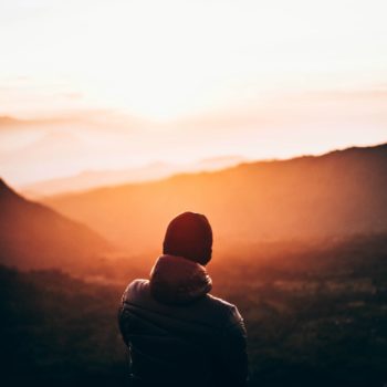 Man facing a sunset over the mountains.