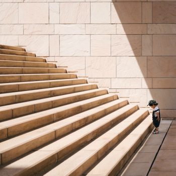 A child standing at the bottom of a large set of stairs