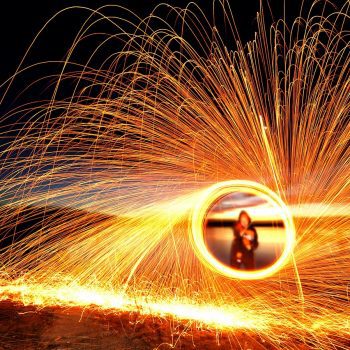 A person in a hooded robe viewed through a ring of sparks