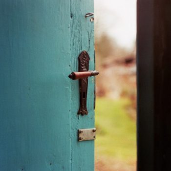 A turquoise painted door open slightly (looking out)