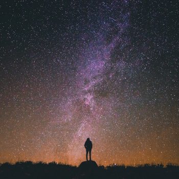 A silhouette of a person looking up at the stars