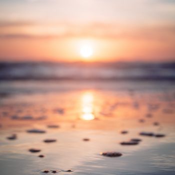 A sunset over a sandy, rocky beach