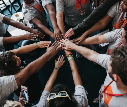 A group of people standing in the circle with their hands joined in the center