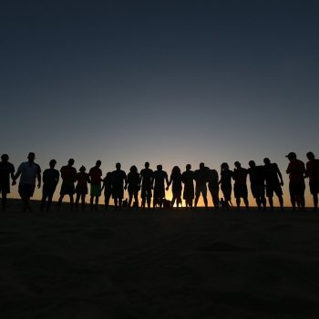 Silhouette of group of people holding hands.