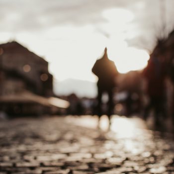 Silhouette of person on a cobblestone street.