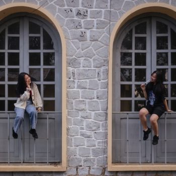 2 people sitting in arched windows smiling at each other