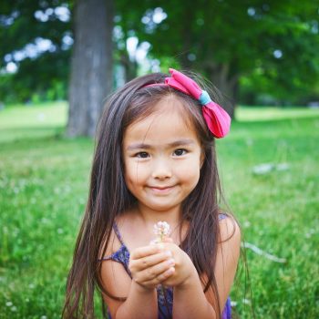 a smiling child holding a flower