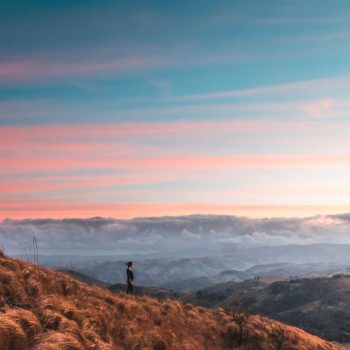 a person standing on brown grasses under blue sky