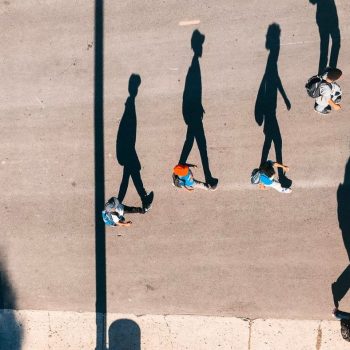 An aerial photo of people walking with their shadows displayed