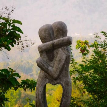 A statue of two hugging figures forming a heart with their legs