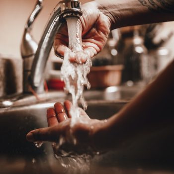 Close up photo of person running hands underneath the water of a faucet