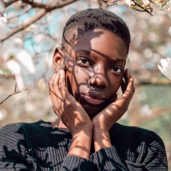 photo of a woman with her hands on her face with trees in the background