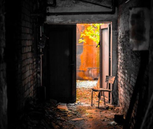 An open door with a rusted tank behind