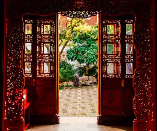 A red ornamental doorway open to a garden space