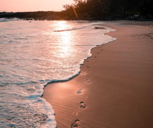 Footprints in the sand of a beach at sunset