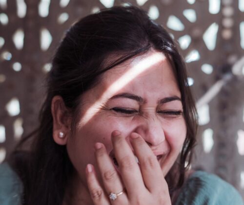 A woman laughing with her hand held to her face