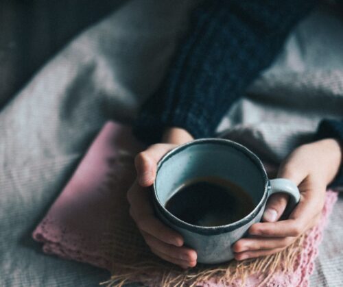 Person holding green mug of coffee