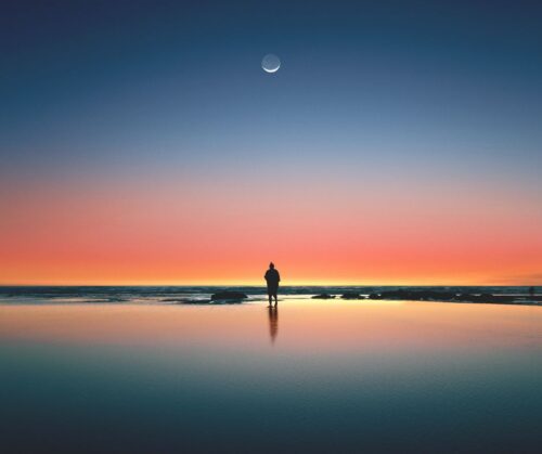 Silhouette of a man standing on seashore under the moon