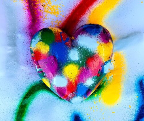 A heart shaped stone spray painted with multiple colors