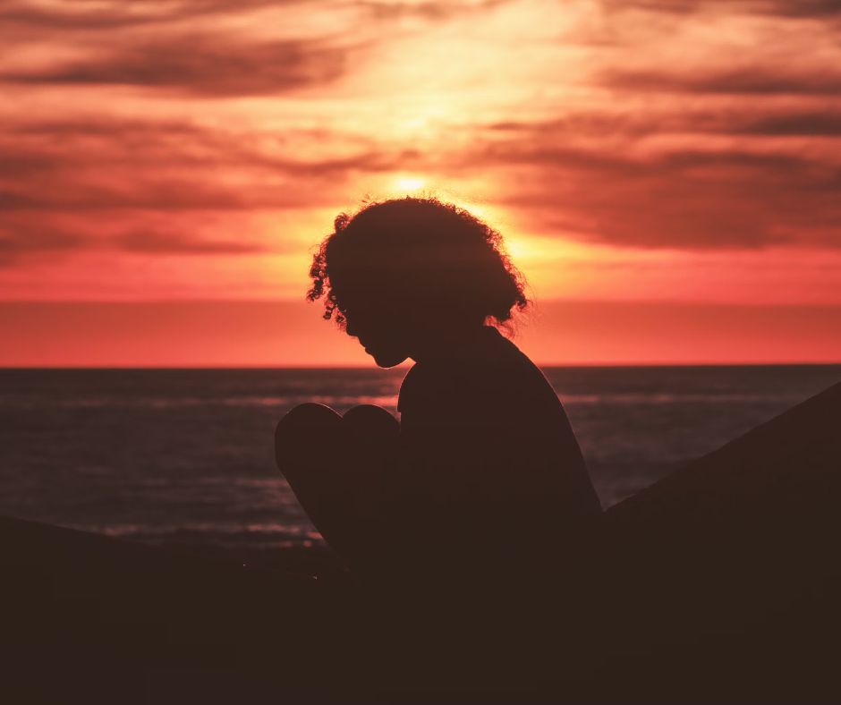 Silhouette of a child near the sea at sunset
