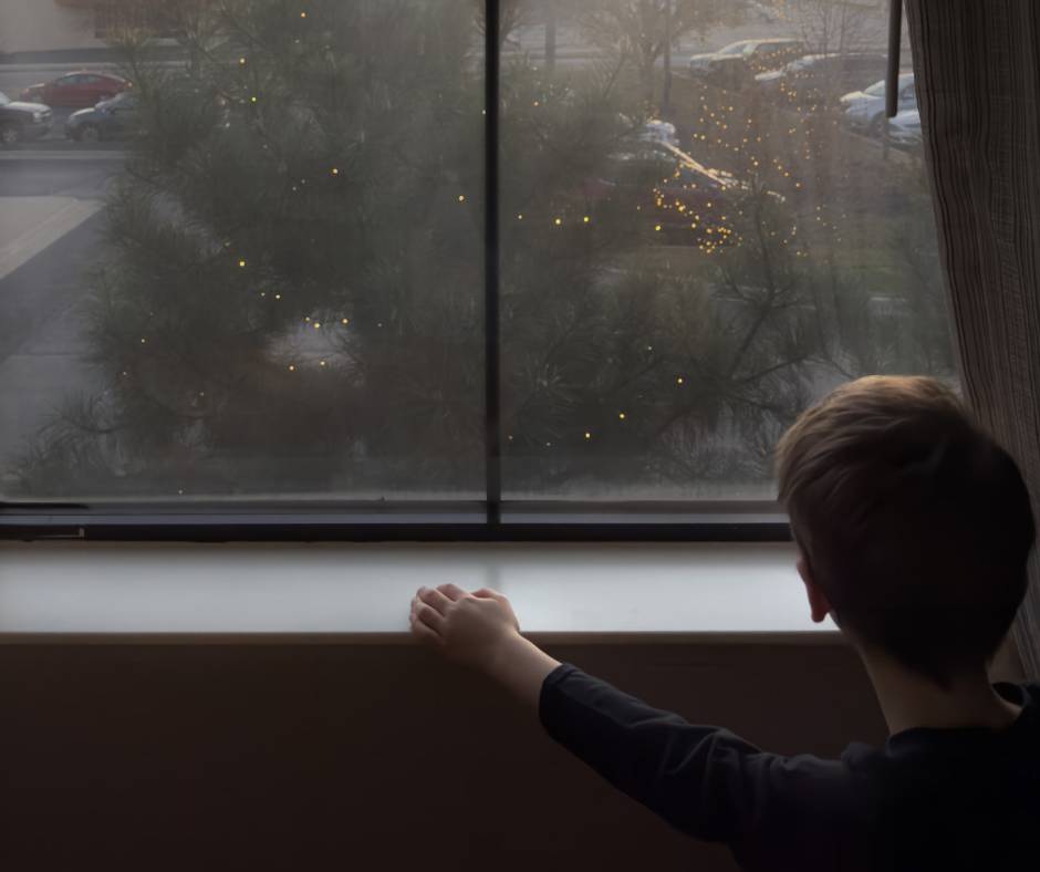 A young boy looking out a foggy window