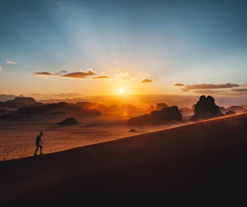 A person walking in the desert at sunset
