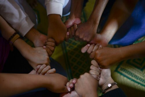 People creating a circle with intertwined hands