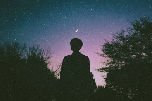 Stars superimposed over silhouette of person looking at night sky
